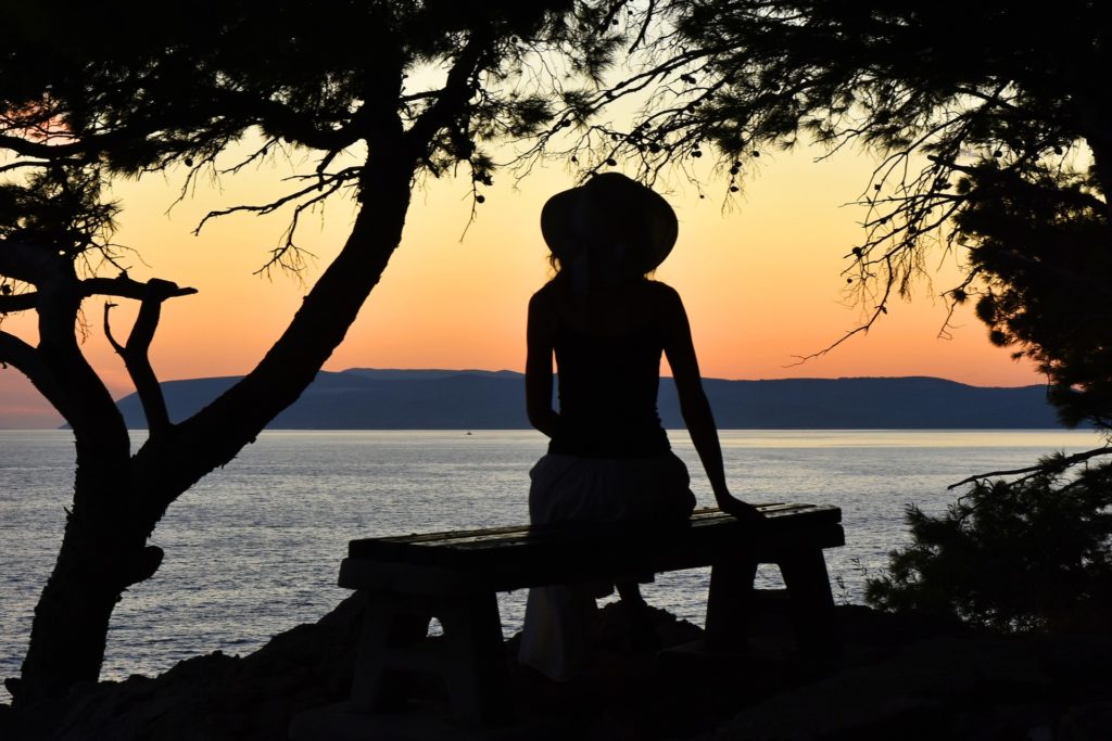 Woman sitting on bench beside ocean